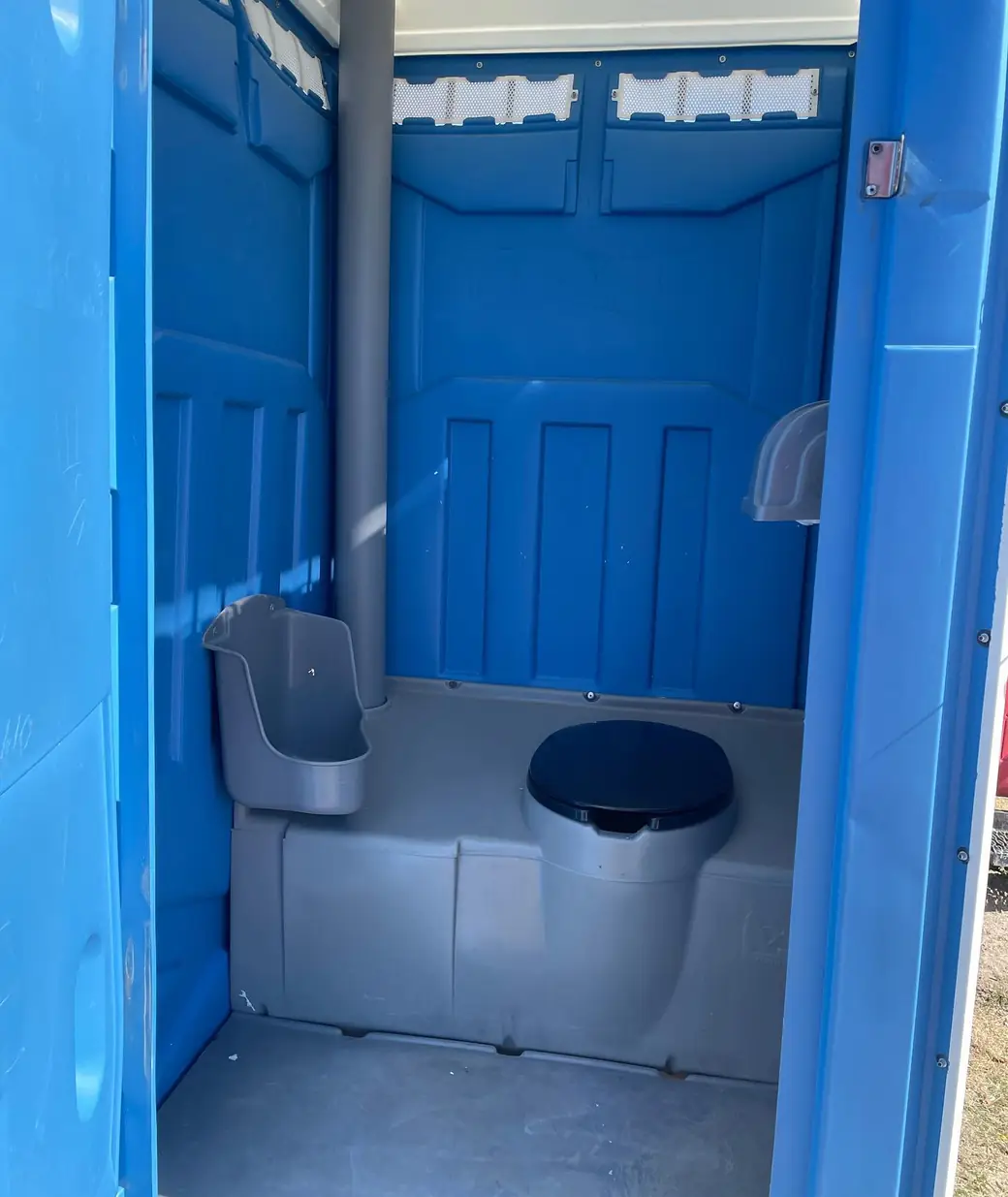 Blue portable toilet interior with seat, urinal and roof vent stack