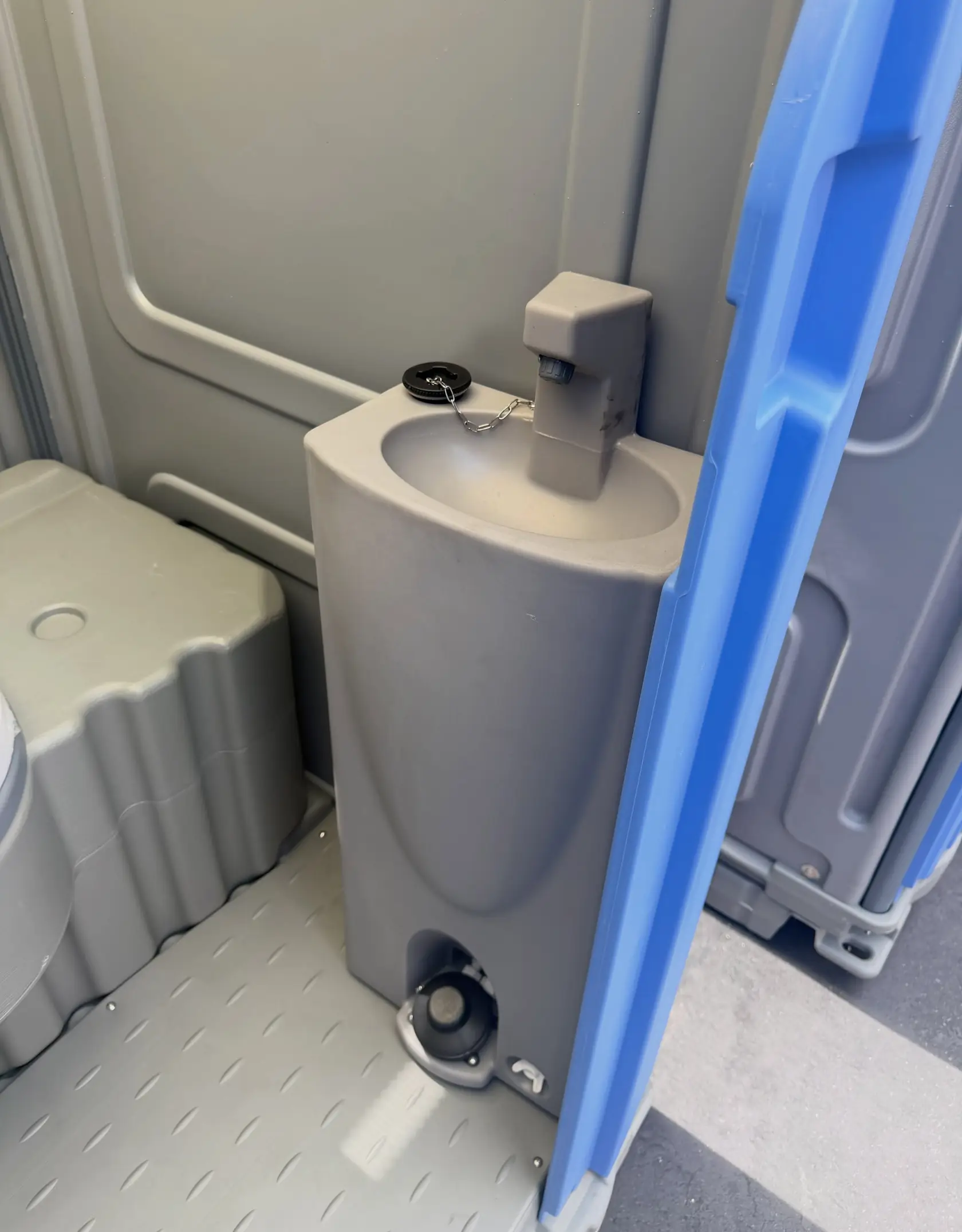 Foot-pump hand sink installed inside a deluxe portable toilet