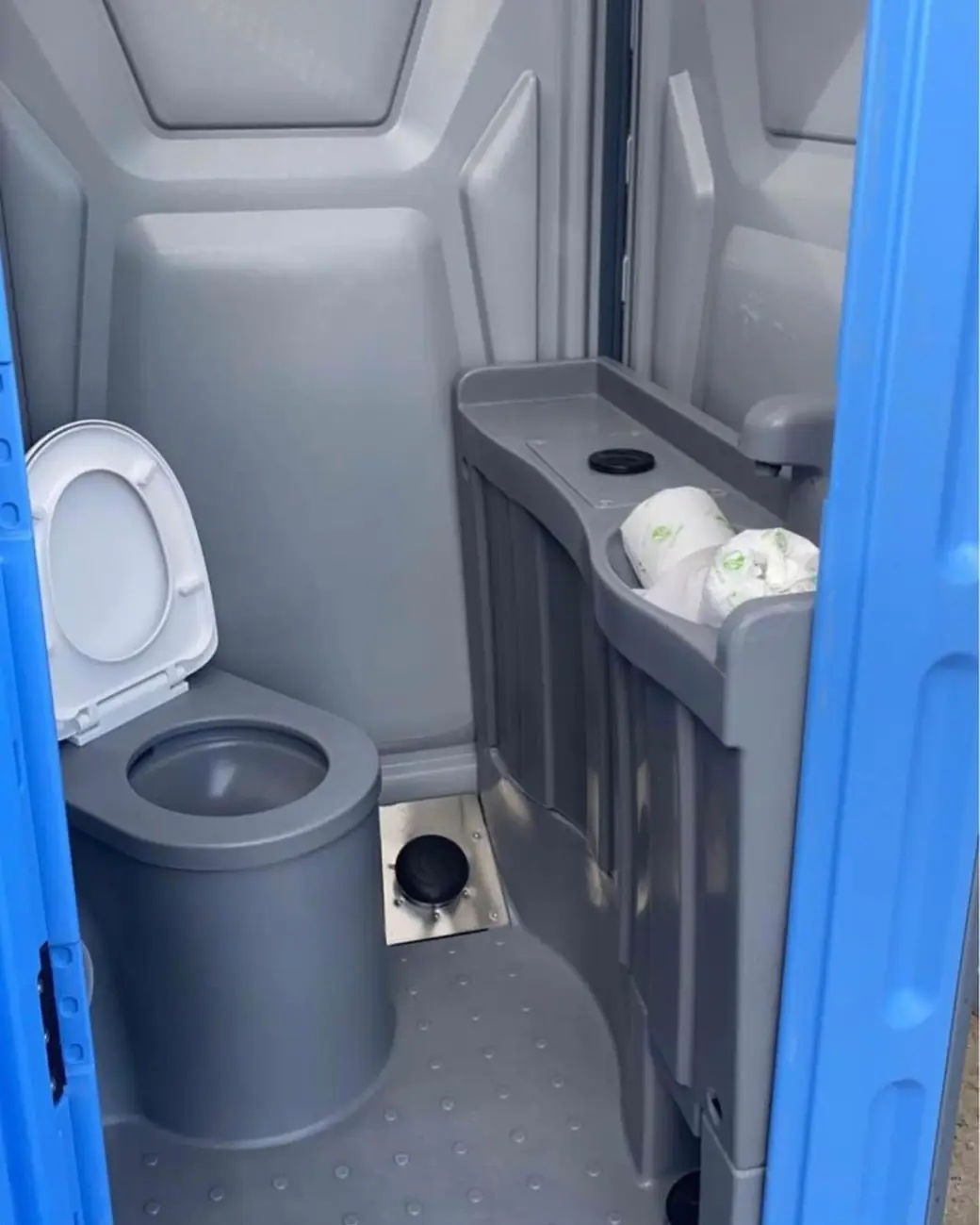 Gray portable toilet interior with a seat and a stocked toilet paper dispenser