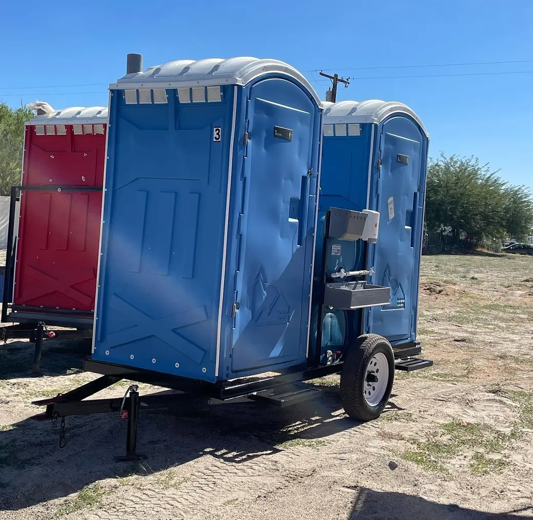 Red and blue portable toilets mounted on a single-axle towable trailer