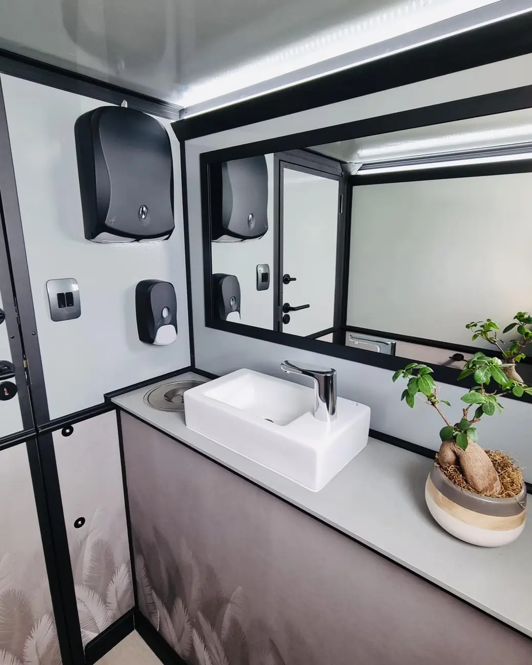 Restroom trailer sink with mirror, soap and paper towel dispensers