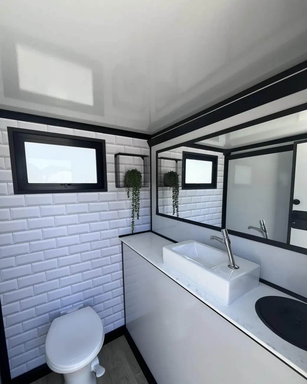 Restroom trailer stall with a subway-tile wall, vessel sink and toilet